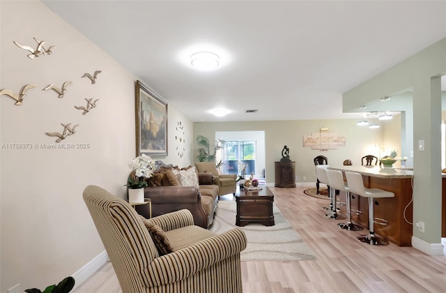 living room featuring light wood-type flooring, baseboards, and visible vents