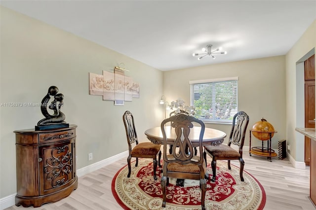 dining room featuring light wood-style floors, baseboards, and a notable chandelier