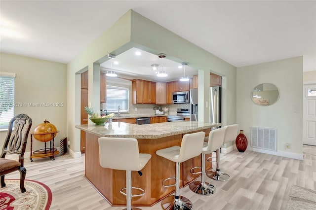 13255 Via Vesta Unit B, Delray Beach, FL 33484 - kitchen with stainless steel appliances, light wood-type flooring, a kitchen bar, a sink, and baseboards