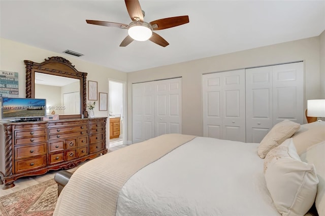 bedroom featuring two closets, ceiling fan, visible vents, and ensuite bath