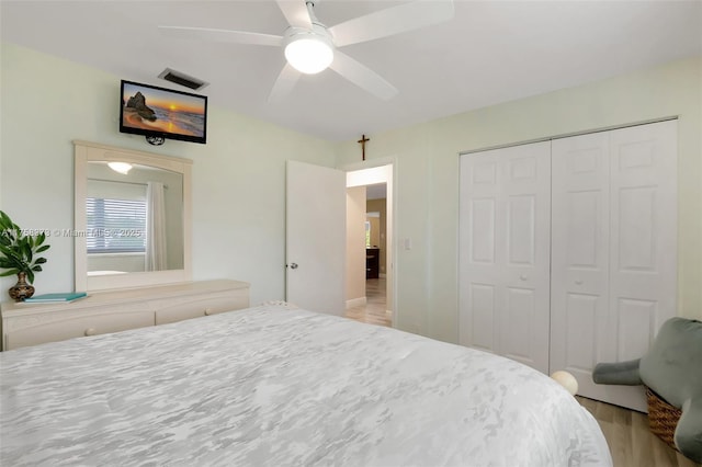 bedroom with visible vents, ceiling fan, wood finished floors, and a closet
