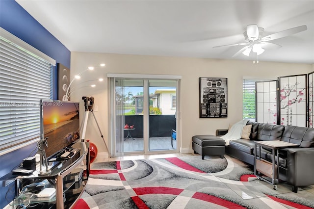 living area with baseboards, plenty of natural light, and a ceiling fan