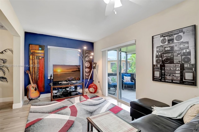 living room featuring baseboards, ceiling fan, and wood finished floors