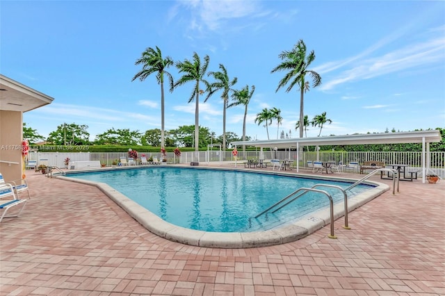 community pool with a patio area and fence