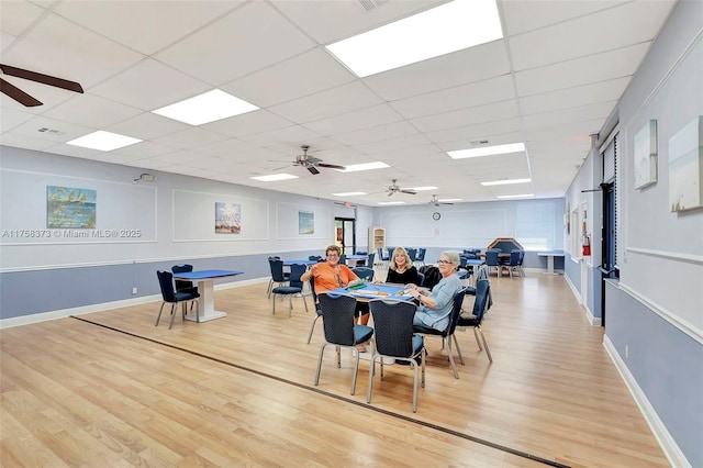 dining room with baseboards, a ceiling fan, a drop ceiling, and light wood-style flooring