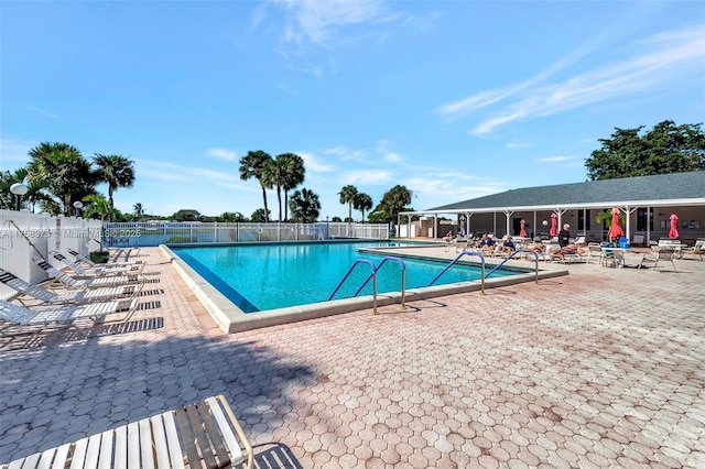 community pool with fence and a patio