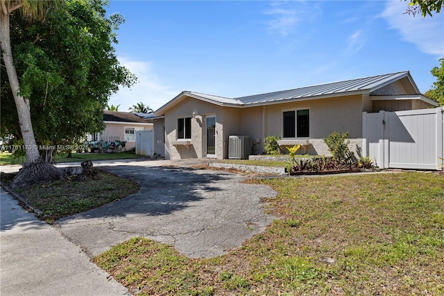 ranch-style home with stucco siding, metal roof, driveway, a standing seam roof, and a gate