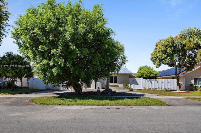 view of front of property featuring stucco siding, driveway, metal roof, and fence