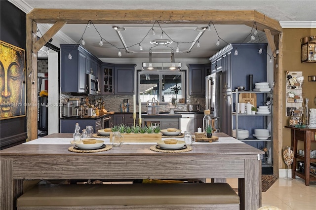 kitchen featuring dark countertops, backsplash, ornamental molding, light tile patterned floors, and stainless steel appliances