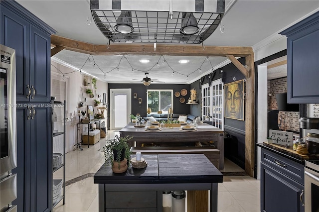 kitchen with light tile patterned floors, a ceiling fan, dark countertops, crown molding, and blue cabinets