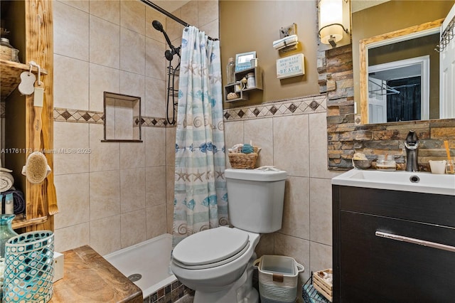 full bath with toilet, a stall shower, tile walls, wainscoting, and vanity