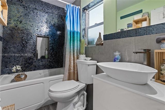 full bathroom with tile walls, vanity, toilet, and shower / tub combo with curtain