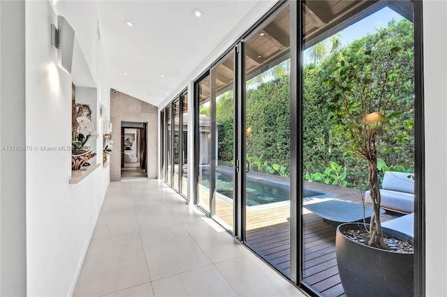 entryway with tile patterned flooring, vaulted ceiling, and expansive windows