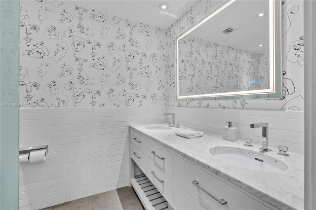 full bathroom with visible vents, wallpapered walls, a sink, wainscoting, and tile walls