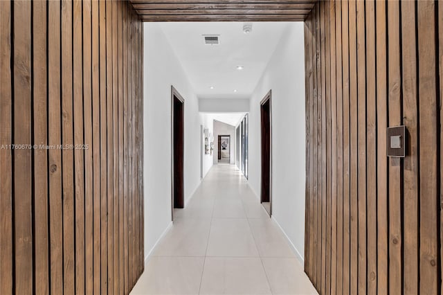 corridor with light tile patterned flooring, visible vents, and baseboards