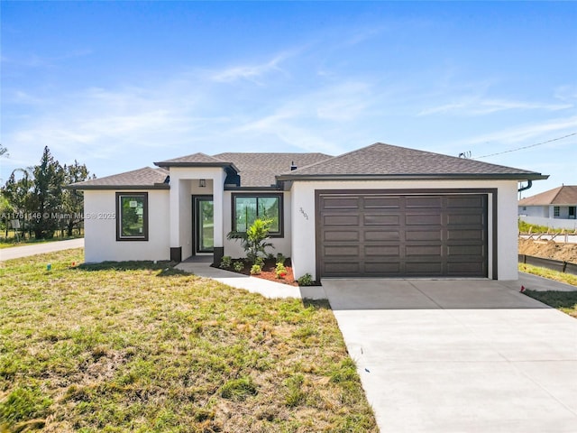 prairie-style house with stucco siding, roof with shingles, concrete driveway, a front yard, and an attached garage