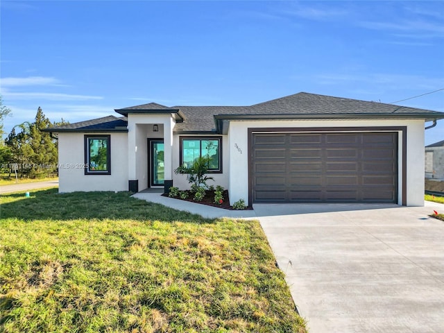 prairie-style house featuring stucco siding, a garage, concrete driveway, and a front yard