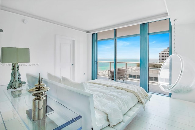 bedroom featuring access to outside, a water view, and expansive windows