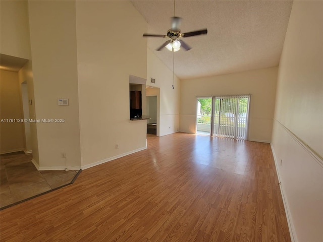 unfurnished living room featuring high vaulted ceiling, a textured ceiling, a ceiling fan, and wood finished floors