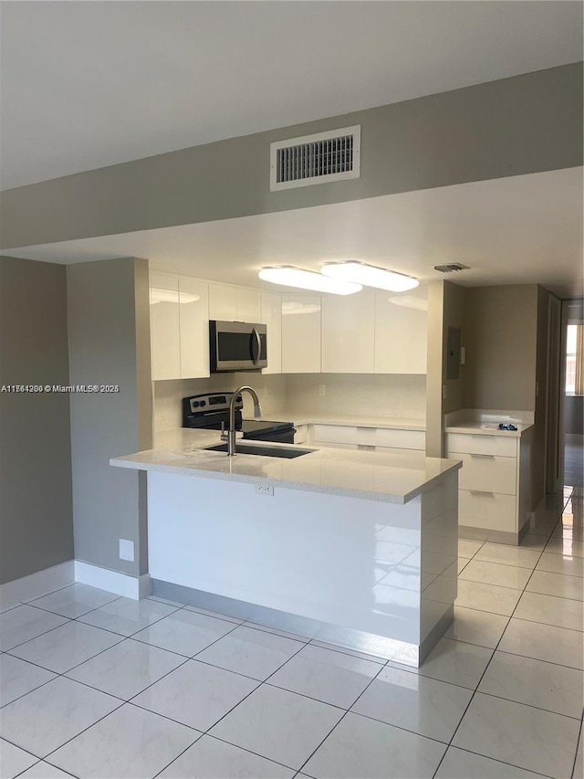 kitchen with visible vents, modern cabinets, a sink, stainless steel microwave, and a peninsula