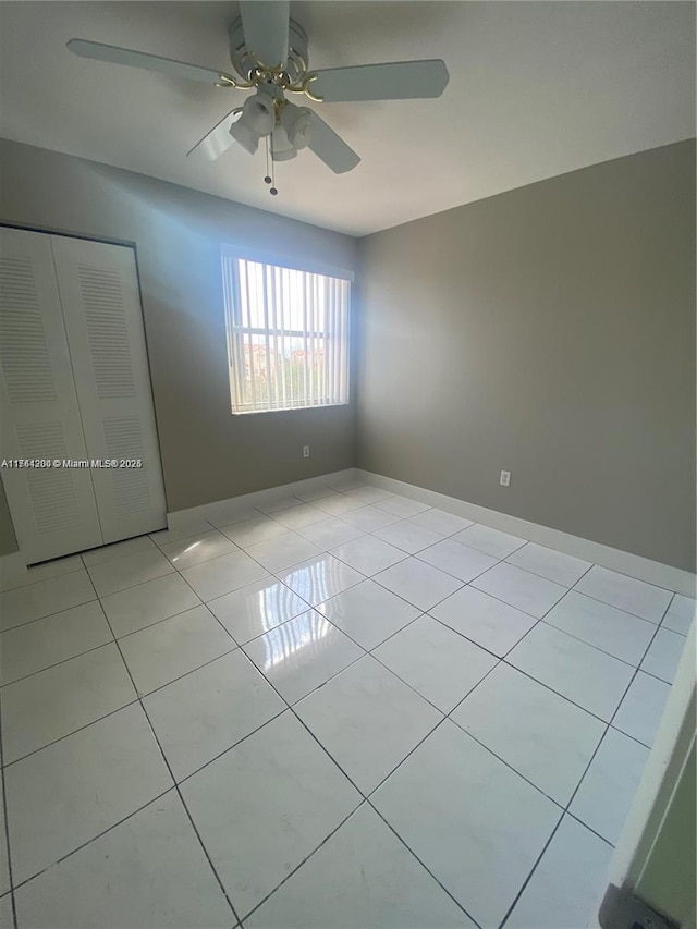 unfurnished room featuring light tile patterned floors, a ceiling fan, and baseboards