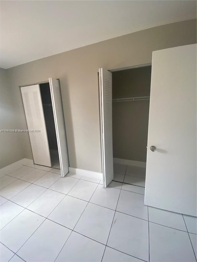 unfurnished bedroom featuring light tile patterned floors, a closet, and baseboards