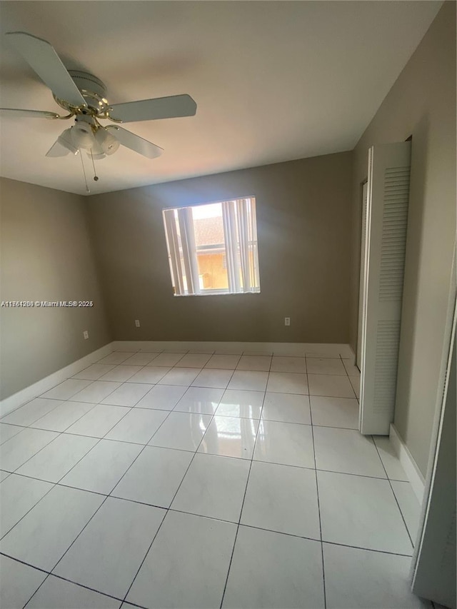 spare room with light tile patterned floors, baseboards, and a ceiling fan