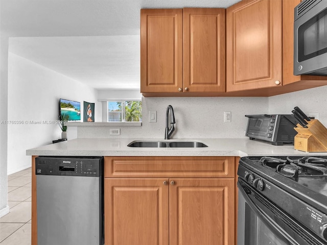 kitchen featuring black gas stove, light countertops, light tile patterned floors, stainless steel dishwasher, and a sink