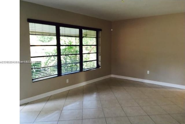 empty room featuring light tile patterned floors and baseboards