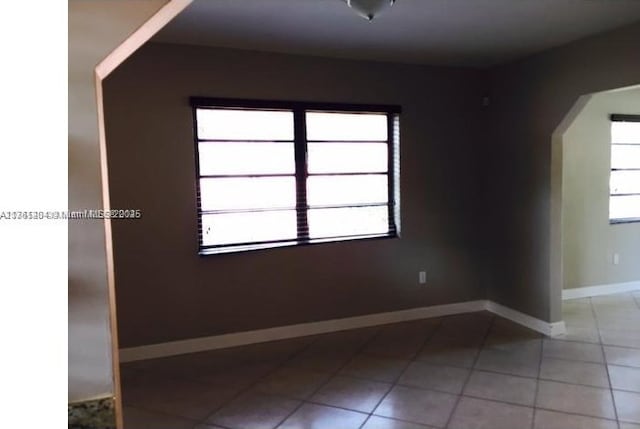 spare room with light tile patterned floors and baseboards