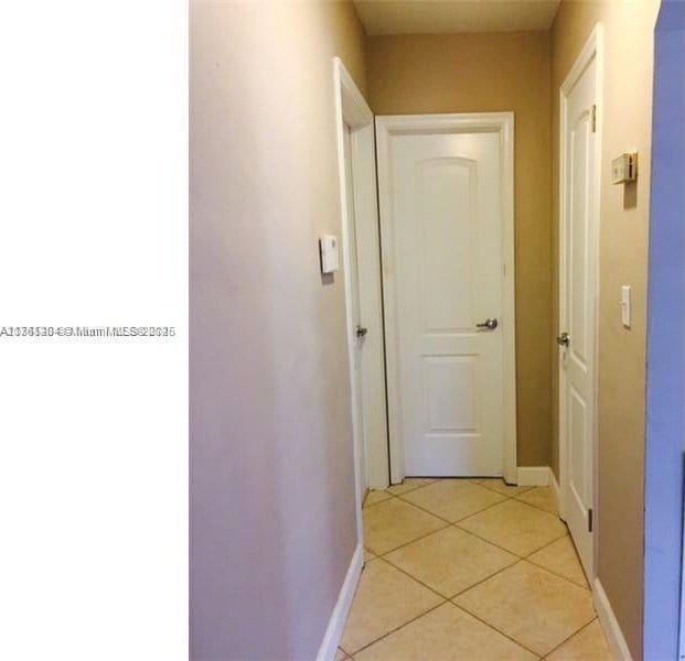 hall with light tile patterned flooring and baseboards