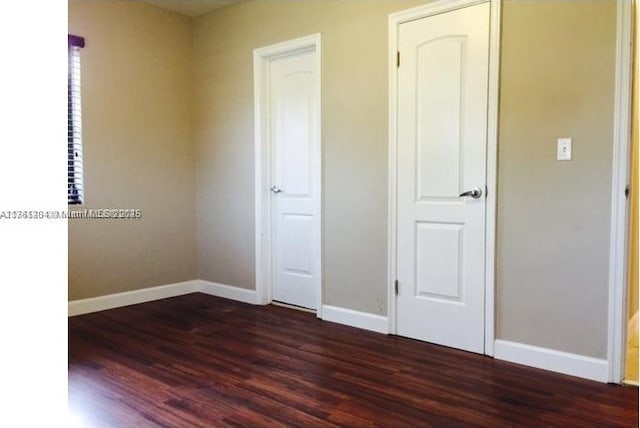 unfurnished bedroom featuring dark wood finished floors and baseboards