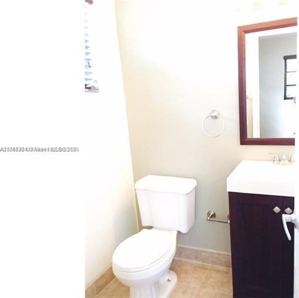 bathroom with baseboards, toilet, vanity, and tile patterned flooring