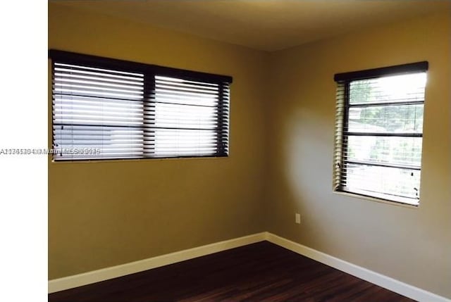 empty room featuring baseboards and dark wood-style flooring