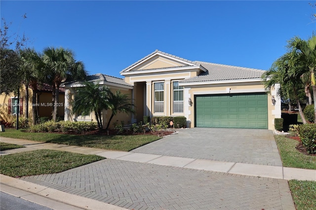 ranch-style house with a tiled roof, decorative driveway, a garage, and stucco siding