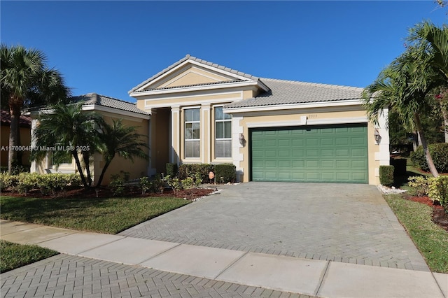 view of front of property featuring a tiled roof, decorative driveway, a garage, and stucco siding