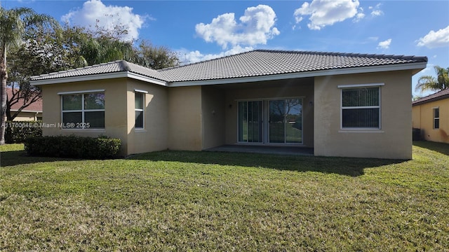 rear view of property featuring a lawn and stucco siding