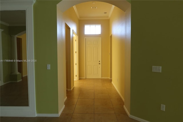 corridor with crown molding, light tile patterned floors, baseboards, and arched walkways