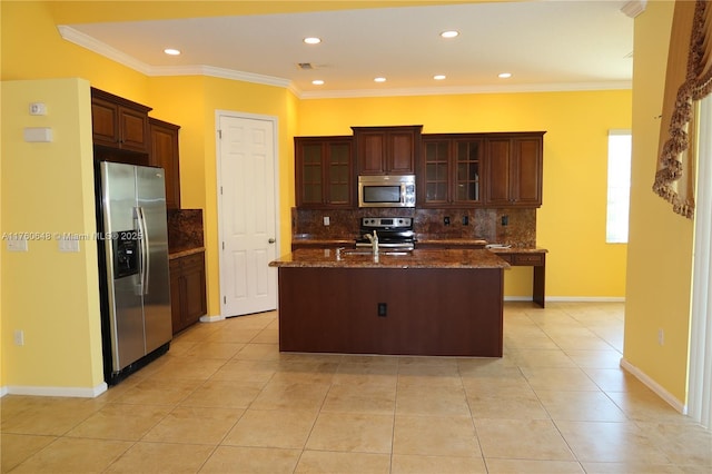 kitchen with light tile patterned flooring, a center island with sink, appliances with stainless steel finishes, and ornamental molding