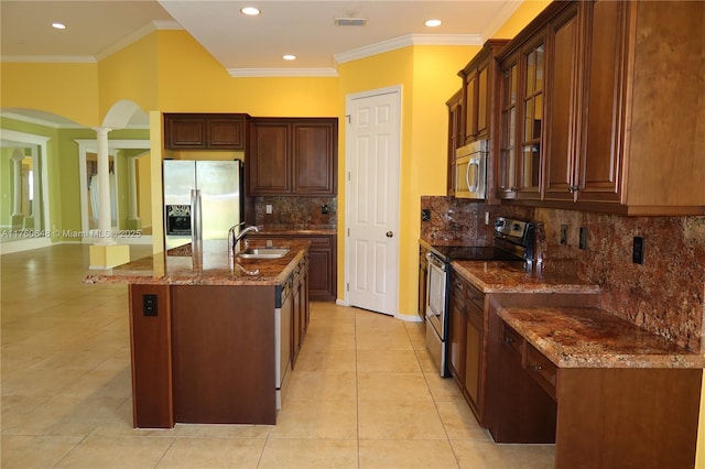 kitchen featuring a sink, stainless steel appliances, ornamental molding, and dark stone counters