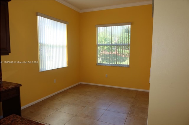 empty room featuring light tile patterned floors, baseboards, a healthy amount of sunlight, and ornamental molding