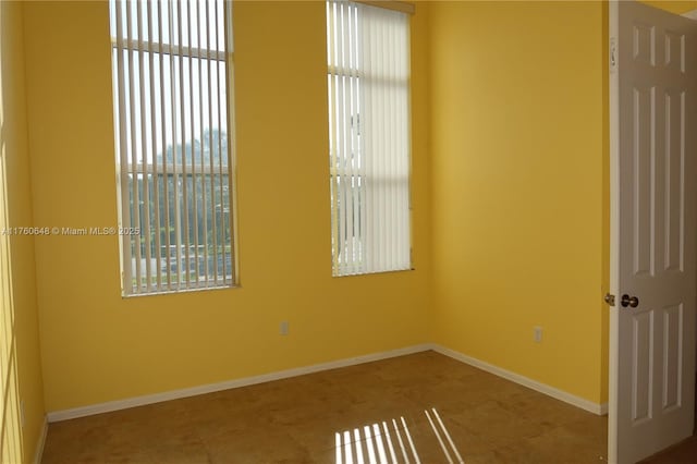 empty room with tile patterned floors, plenty of natural light, and baseboards