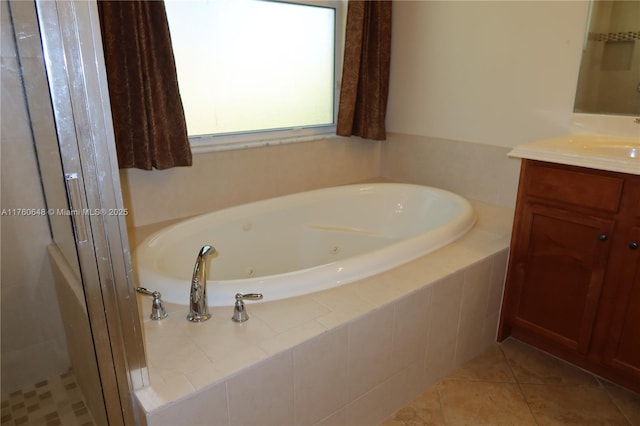 full bath featuring a jetted tub, vanity, and tile patterned flooring