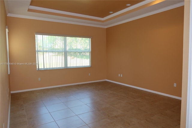 spare room with a raised ceiling, baseboards, and ornamental molding