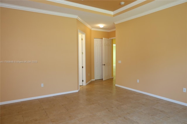 empty room featuring a raised ceiling, crown molding, and baseboards