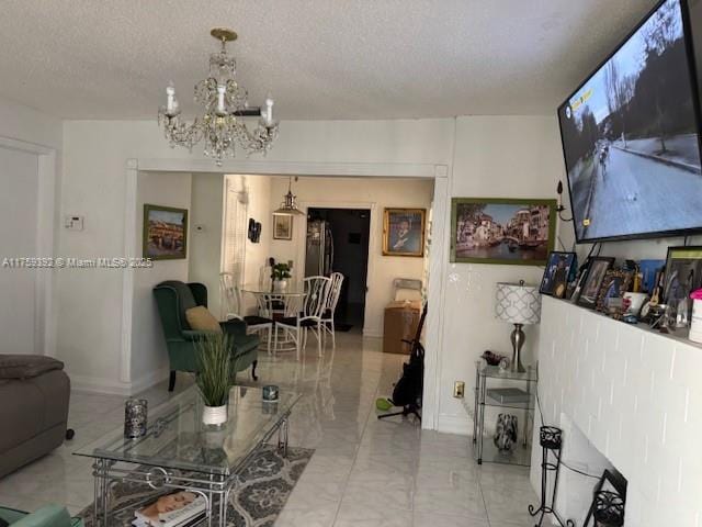 living area with a chandelier, marble finish floor, a textured ceiling, and baseboards