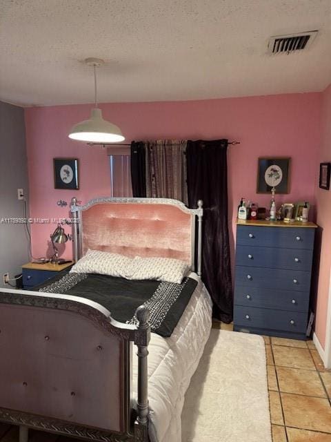 bedroom with light tile patterned floors, visible vents, a textured ceiling, and baseboards