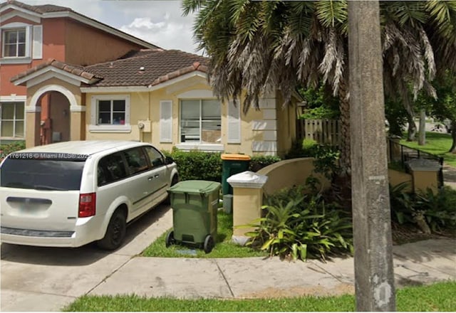 view of front of home featuring stucco siding, fence, and a tile roof