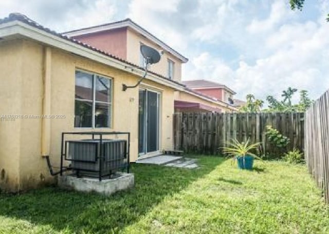 rear view of house featuring stucco siding, a yard, and fence