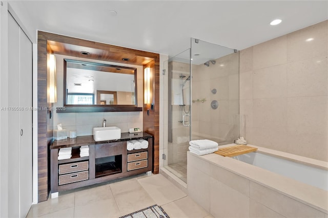 full bath featuring tile patterned floors, a garden tub, tile walls, a shower stall, and vanity